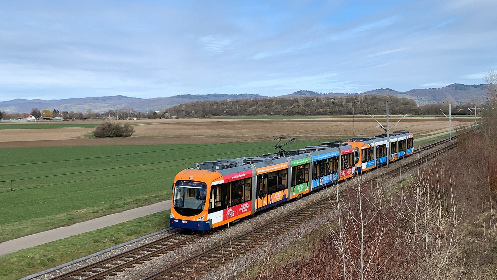 Ein RNV6Z-Verband vor Bergstraßen-Panorama auf der Strecke zwischen Weinheim und Viernheim