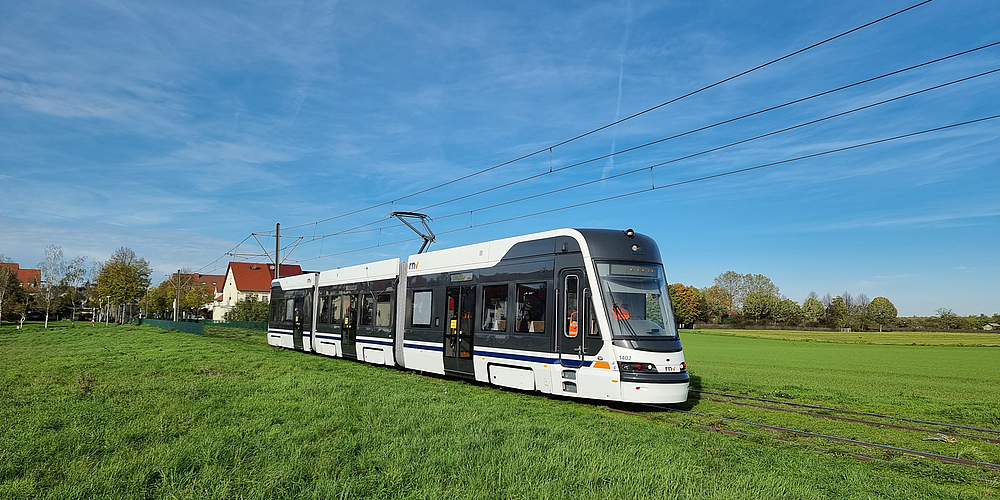 Eine Stadtbahn des neuen Typs RNT fährt durch eine grüne Landschaft