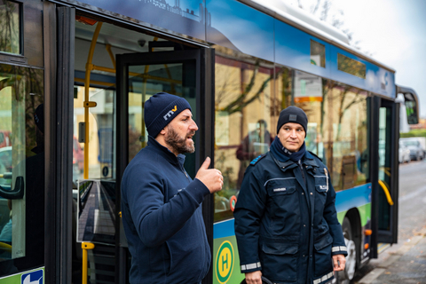 Ein rnv-Mitarbeiter und ein Polizeibeamter der Jugendverkehrsschule Mannheim stehen vor dem Bus der rnv-Busschule und erklären, wie man sich an einer Bushaltestelle sicher verhält.