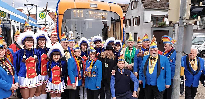 Narren und Närrinnen vor der Straßenbahn