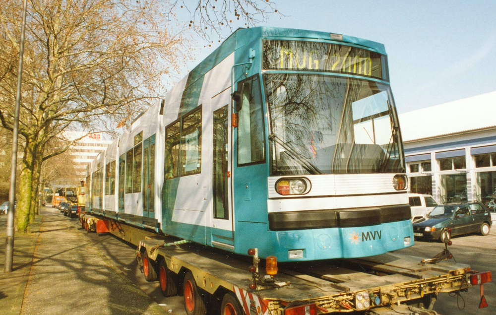 Eine türkise Straßenbahn steht auf einem Tieflader.