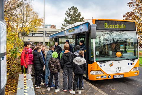 Eine Schulklasse vor dem Bus der rnv-Busschule an der Haltestelle für den Schulbus ihrer Schule.