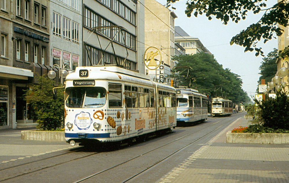 Mehrere ältere, kurze Straßenbahnen fahren durch die Mannheimer Fußgängerzone.