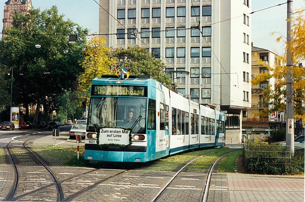 Eine türkisene Straßenbahn fährt in eine Haltestelle ein.
