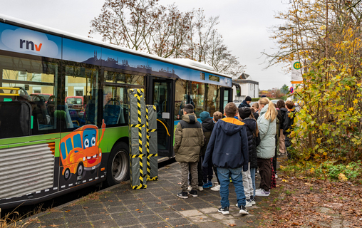 Eine Schulklasse vor dem Bus der rnv-Busschule an der Haltestelle für den Schulbus ihrer Schule.