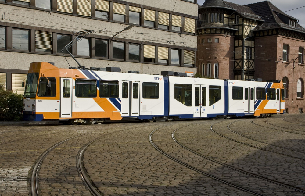 Eine modernisierte, nun orange-blaue Straßenbahn steht auf dem Betriebshof in Heidelberg.