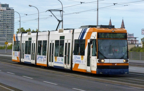 Eine orange-blaue Straßenbahn überquert die Konrad-Adenauer-Brücke nach Mannheim.